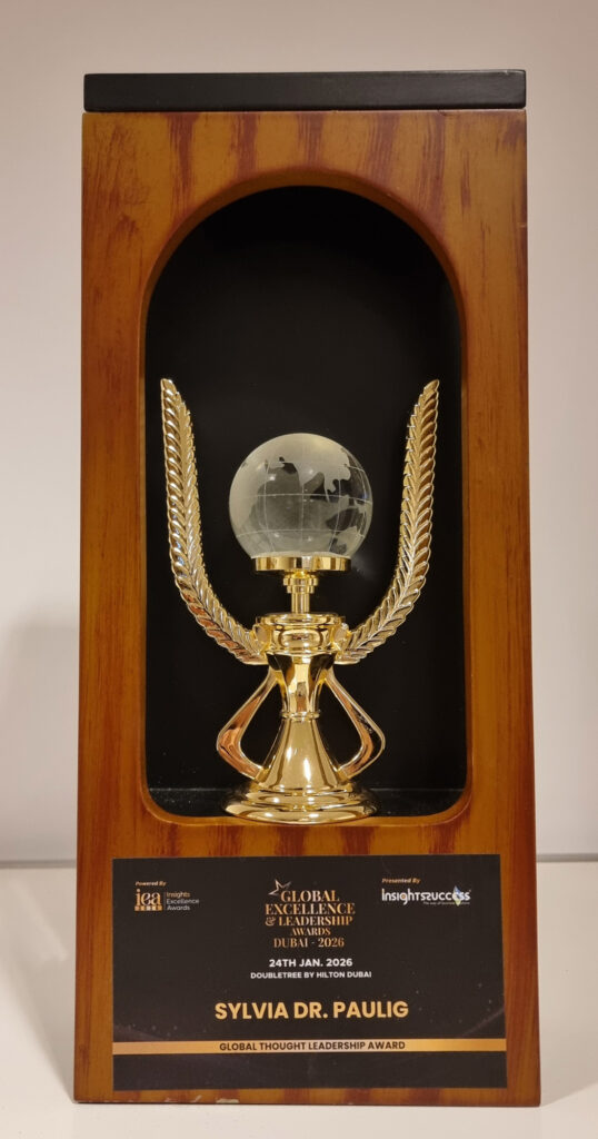 Sylvia Dr Paulig erhält einen goldenen Award mit Glasglobus auf dunklem Holzsockel