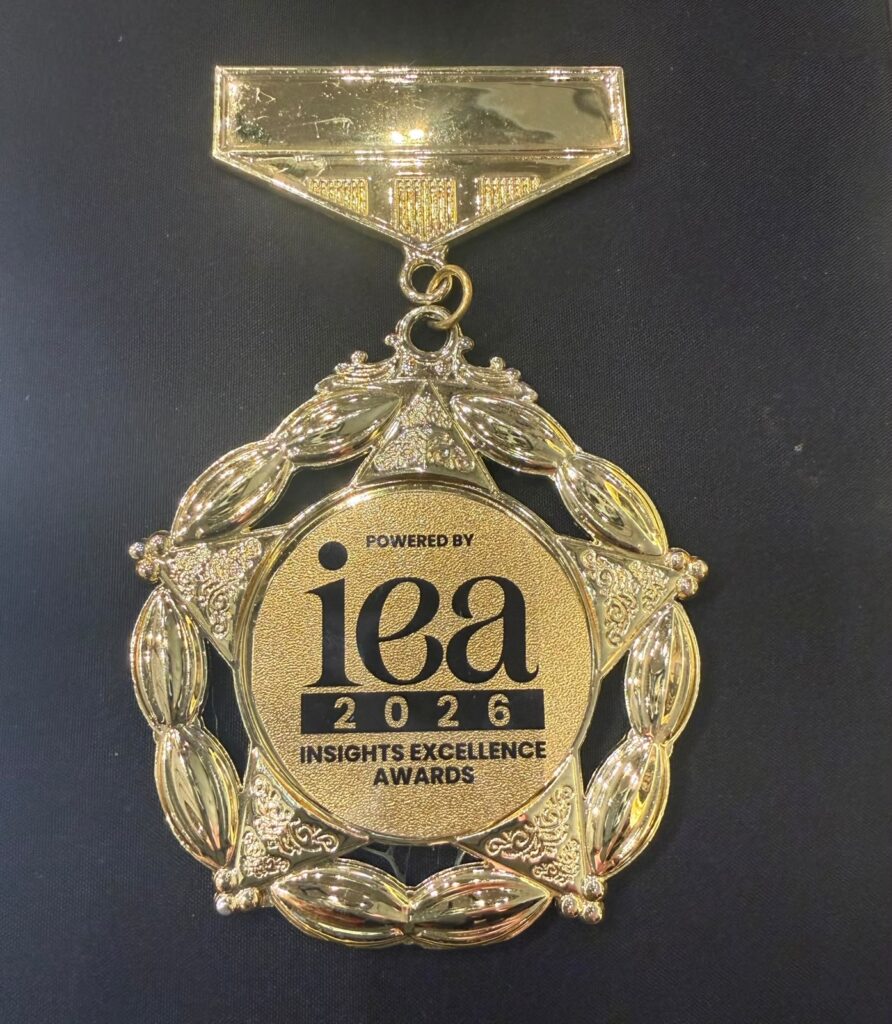 Goldene Medaille mit Lorbeerkranz und iea Schriftzug 2026 auf Schwarz